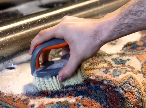 Silk rug cleaning by a worker using a brush
